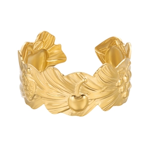 Macro shot of gold embossed wide cuff bracelet with fruit and leaf pattern carvings