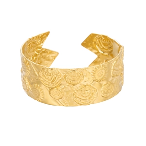Detail of wide gold stainless steel cuff featuring embossed sun patterns and textures