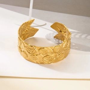 Detail of bohemian gold wide open cuff bracelet with sun and face relief patterns