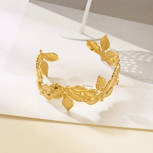 Macro shot of gold-plated open bangle featuring intricate laurel leaf texture and finish