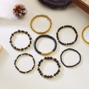 Detail of seven-piece bohemian stretch bracelet set with black beads and gold accents