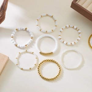 Flat lay of 7-piece bohemian beaded bracelet set featuring white and gold accents