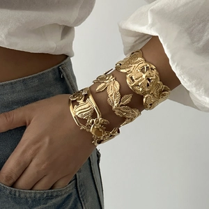 Golden wide open bangles featuring leaf and sea shell relief designs on model
