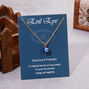 Collier chaîne dorée avec pendentif œil bleu maléfique présenté sur carte cadeau foncée