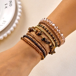Close-up of bohemian multi-layer beaded bracelets with brown stone and gold accents