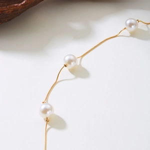 Détail d'une ceinture chaîne dorée avec perles blanches pour décoration de robe de soirée