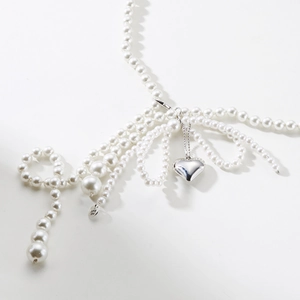 Détail de la chaîne de taille en perles avec nœud papillon et pendentif cœur argenté