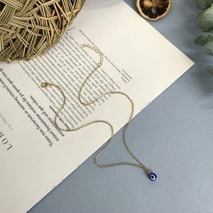 Collier bohème plaqué or avec pendentif œil bleu pour femme sur fond de magazine