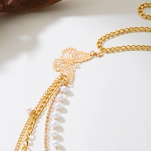 Détail de la chaîne de taille papillon dorée avec perles, strass et pampilles délicates