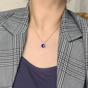 Collier chaîne dorée avec pendentif Evil Eye bleu porté par une femme mannequin