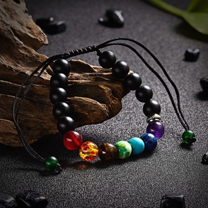 Macro shot of obsidian beaded bracelet with seven chakra stones on weathered wood
