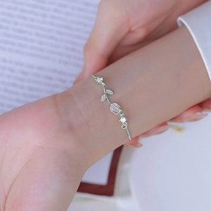 Detail of silver tulip bracelet with cat eye stone and diamonds on a wrist