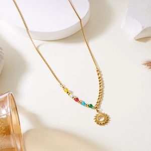 Détail du collier pendentif soleil doré avec perles colorées et chaîne asymétrique