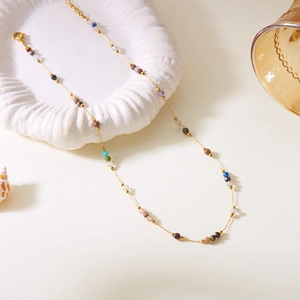 Détail d'un collier en acier inoxydable doré avec perles en pierres naturelles multicolores