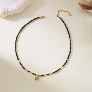 Detail of beaded star necklace with black stones and golden stainless steel star pendant