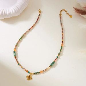 Detail of bohemian natural stone beaded necklace with gold floral pendant and steel tag