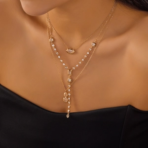 Close-up of layered gold necklace set with cubic zirconia pendants on a model