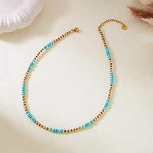 Detail of bohemian necklace featuring sky blue beads and golden lobster clasp closure