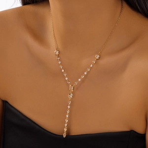 Detail of a 18K gold Y-shaped necklace with geometric zircon stones on a model