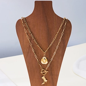 Detail einer goldene Doppelkette mit Cowboyhut- und Stiefelanhängern im Western-Stil