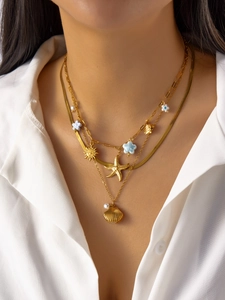 Detalle de collar dorado de varias capas con colgantes de estrella de mar y sol