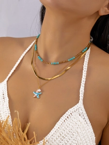 Primer plano del collar bohemio de tres capas con colgante de estrella de mar y cuentas