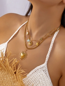 Detalle de collares dorados en capas con dijes de estrella de mar y concha estilo playa