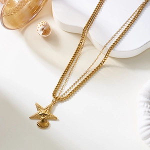 Detalle de collar dorado de capas con colgantes de estrella de mar y concha marina