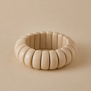 Macro view of beige resin elastic bracelet with smooth rounded rectangular beads