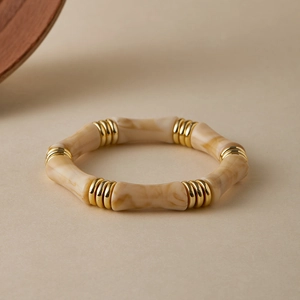 Dettaglio macro del bracciale in resina effetto bambù con eleganti distanziali d'oro