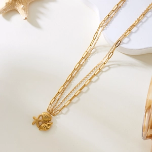 Detalle de collar dorado de varias capas con colgantes de concha y estrella de mar