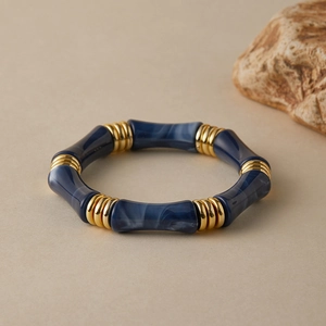Dettaglio del bracciale in resina marmorizzata blu con anelli metallici dorati testurizzati