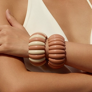 Modern geometric ribbed resin bracelets in beige and pink tones on a female model