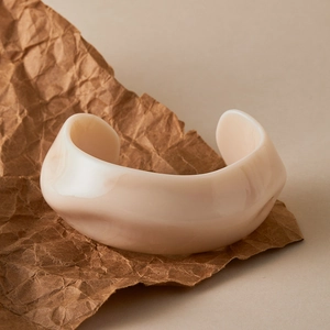 Macro view of wide irregular open bangle with beige acrylic marbling and glossy finish