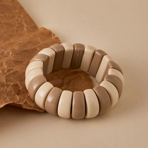 Detail of beaded stretch bracelet with brown and cream resin beads on kraft paper