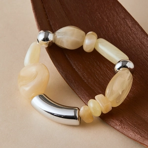 Detail of irregular marble-textured beads and polished silver metal tube on wood