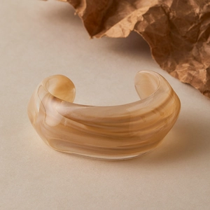 Macro detail of acrylic marble resin cuff bracelet with brown and cream swirl texture