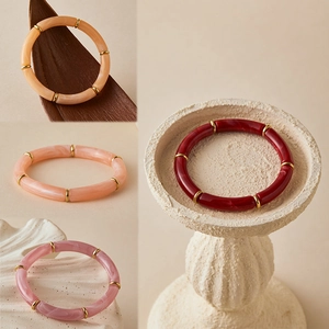 Detail van kleurrijke acryl bamboe armbanden met marmertextuur en gouden metalen kralen