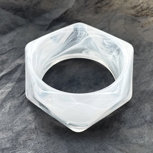 Dettaglio del bracciale esagonale in resina con trama marmorizzata bianca stile moderno
