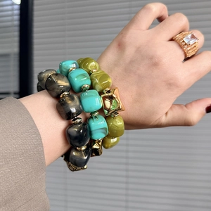 Macro detail of stacked vintage resin bracelets with black gold and turquoise patterns