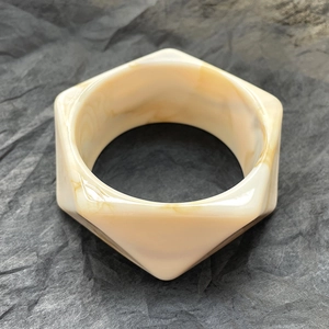 Dettaglio di un bracciale esagonale in resina con trama marmorizzata ambrata
