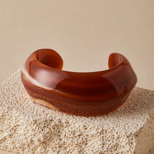 Macro detail of amber resin cuff bracelet showing natural beige swirl marble texture