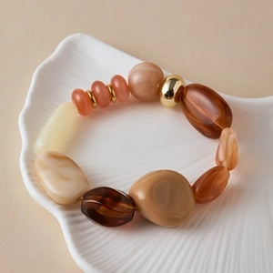 Detailed shot of bohemian beaded bracelet with amber resin stones on white ceramic dish