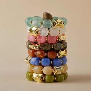 Chic acrylic resin bead bracelets with marble texture and gold accents on a wooden stand