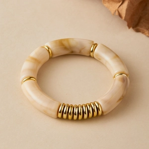 Detailed macro view of ivory marble resin beads and golden metallic rings on the bracelet