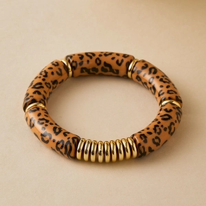 Macro detail of elastic leopard print beads and polished gold metal rings bracelet