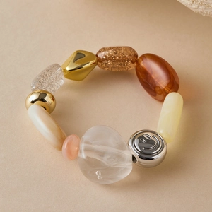 Detail of beach style beaded bracelet with smile engraving and irregular amber resin beads