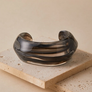 Macro view of wide acrylic open cuff bracelet with smoky brown marble texture on stone