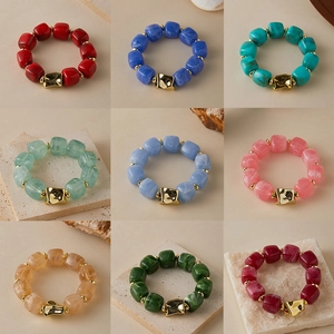 Close-up of handmade geometric marble resin bead bracelets with gold accents in various colors