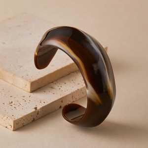 Detail of retro acrylic cuff bracelet with brown marble texture on travertine stone
